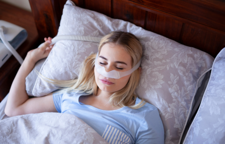 A woman sleeps wearing a CPAP machine.