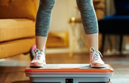 Woman stands on a vibration plate device
