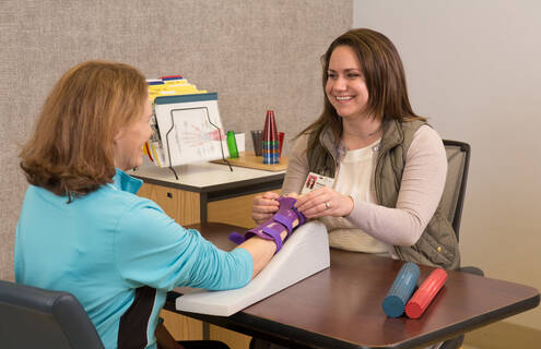 A provider helps a patient with rehab on her arm