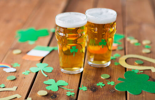 Two glasses of beer on a table decorated with green shamrocks