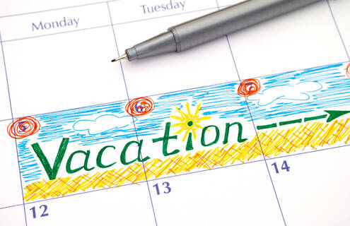 A paper calendar page with the word "Vacation" written across several days in colorful ink