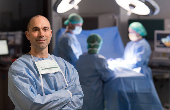 Matthew J. Nofziger, MD, stands in the foreground, while other providers perform surgery in the background