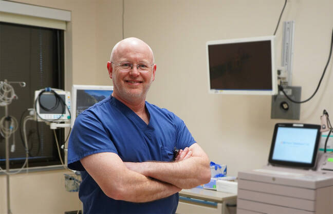 A male healthcare provider stands in an examination room
